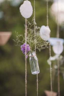 Düğün dekoru, çiçekli şişeler ve yeşil arka planda Shell Mobile. Mini vazo ve tavandan sarkan çiçek buketleri şeklinde orijinal düğün çiçekleri.. 