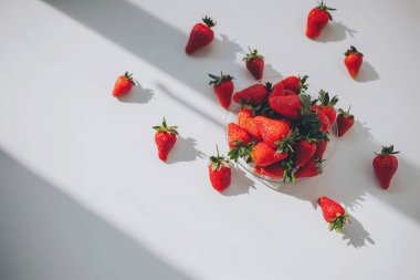 Beyaz masada çilekli yaz arkaplanı. Penceredeki gölgelerle ışık arkaplanı, kopyalama alanı.