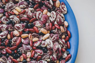 Bir sürü karışık fasulye serpiştirdim. Fasulye çeşitliliği. Farklı fasulye çeşitleri. Üst Manzara. mavi tabakta