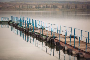 Gündüz vakti gölün üzerindeki tahta iskelede. Sahildeki tekneler için uzun rıhtım.