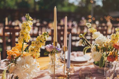 Çiçekler ve mumlarla ahşap düğün masası süsü. Mumlar ve çiçekler