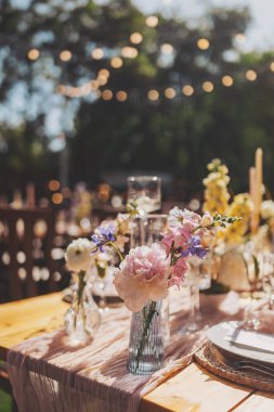 Aile yemeği ya da dışarıda toplanmak için güzel bir dekorasyon masası. Güneşli bir günde. Düğün töreni, özel parti. Gece için lamba asmak.