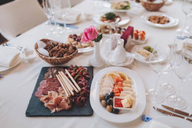 Lezzetli yiyeceklerle süslenmiş güzel bir masa. Lezzetli atıştırmalıklar ve sıcak bir atmosferle öğle ya da akşam yemeği için her şey hazır. Balık tabakları, salatalar ve abur cuburlarla bir tatil masası servis etmek..