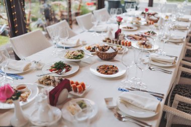 Lezzetli yiyeceklerle süslenmiş güzel bir masa. Lezzetli atıştırmalıklar ve sıcak bir atmosferle öğle ya da akşam yemeği için her şey hazır. Balık tabakları, salatalar ve abur cuburlarla bir tatil masası servis etmek..
