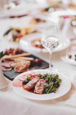 Beyaz masa örtüsü üzerinde yemek. Lokantadaki şefin masasında bir sürü farklı yemek var.. 