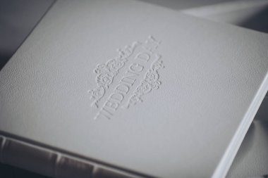 Kabartma kelimelerle dolu bir fotoğraf kitabı. Gerçek deri kapağında düğün günü. Profesyonel bir fotoğrafçı ve tasarımcının hizmetleri. beyaz deri dokusu.