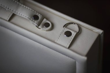 Deri kutunun içindeki beyaz düğün fotoğraflarının ayrıntıları. Fotoğraf kitapları için şık bir hediye kutusu. Bej renkli hediye kutusunda perçin ve saplı beyaz aile fotoğrafı. fotoğraf albümü deri kutuda. 