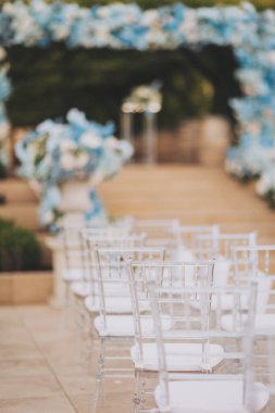 Modern şeffaf sandalyelerle dekore edilmiş seremoni alanı. Düğün töreni detayları. Lüks bir düğün töreninde konuklar için sandalyeler