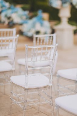 Modern şeffaf sandalyelerle dekore edilmiş seremoni alanı. Düğün töreni detayları. Lüks bir düğün töreninde konuklar için sandalyeler