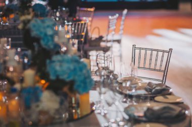 Düğün masası ayarları. Şölen masası tabaklar, çatal bıçaklar, bardaklar, mumlar ve çiçek düzenlemeleri ile süslenir.. 