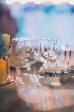 Şatafatlı yemek masaları ve cam eşyalar, bardağa şarap doldurmak. Güzel bulanık arkaplan. Tatil düğünü için hazırlık. Lüks bir restoran..