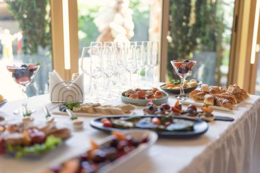 Düğünde soğuk, sıcak aperatiflerle birlikte ziyafet masası servis edildi. Abur cuburlarla dolu bir masa, düğün için yemek servisi. Kurumsal catering etkinliğinin büfe masasında çeşitli atıştırmalıklar ve içecekler.