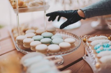 Misafirler için bir sürü lezzetli pasta ve tatlı. Lezzetli düğün resepsiyonu, tatlı masası. Bir garsonun kadın eli bir restoranda açık büfe masası için yemek hazırlar.