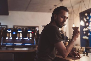 Modayı takip eden baristanın kahve molası var ve kahvesinin tadını çıkarıyor. Yakışıklı barista kafede yeni bir çeşit kahve tadıyor..