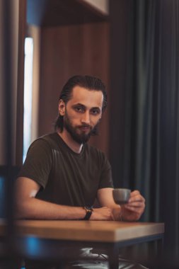 Elinde kahve fincanı espresso tutan gülümseyen genç sakallı adam. Adam sabah taze ekspres kahve içiyor.. 