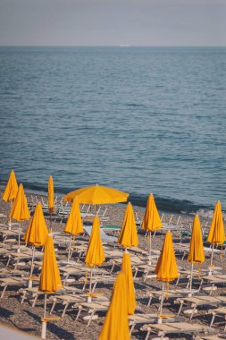 Tatil sezonu - deniz sahilinde günbatımı kumsal şemsiyeleri, denizde tatiller. Plaj şemsiyeleri. Kanvas sandalyeler ve şemsiyeler yayılır ve akşamları plaja yayılmazlar.. 