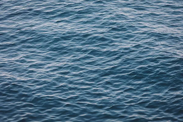 Işık altında deniz suyu akışının soyut bir arka planı. Sakin dalgalı bir deniz resmi.. 