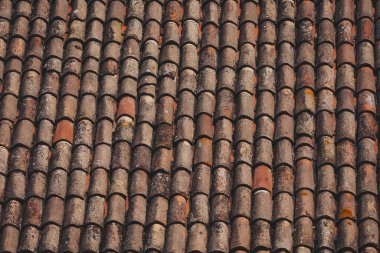Eski çatının eskimiş kiremitleri. Ortaçağ binasının çatısındaki yıpranmış paslı kırmızı fayansların dokulu arka plan için yakın plan. 