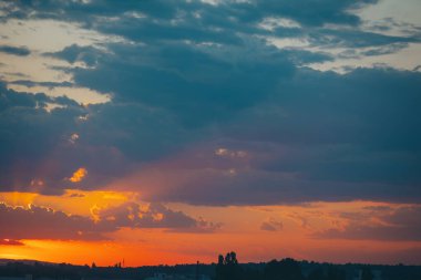 Bulutlu güzel günbatımı arkaplanı. Karşıt mavi gökyüzü ile altın gün batımı. Şehrin çatılarında bulutlarla dramatik günbatımı. 