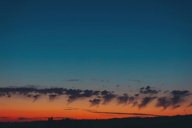 Bulutlu güzel günbatımı arkaplanı. Karşıt mavi gökyüzü ile altın gün batımı. Şehrin çatılarında bulutlarla dramatik günbatımı. 