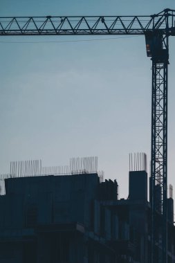Akşam gökyüzünde turnalar. Bir vinç silueti ve inşaat halindeki bir binanın mavi gökyüzü.. 