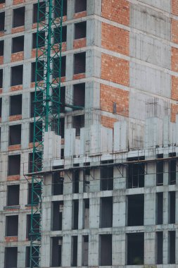 Beton panellerden yapılmış modern bir binanın ön cephelerinin yapımı, yakın plan. Bir sürü yeni kat. Endüstriyel iskelesi olan bir apartman inşaatı