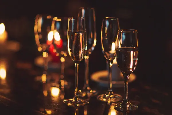 Karanlıkta mum ışığında şampanya gazları. Partide alkol kokteyli. Parti ve tatil kutlaması konsepti.