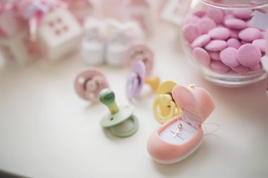 Bebek ayakkabıları, emzikler, pembe kutular ve vaftiz için haç. Doğum günü partisi ya da bebek partisi