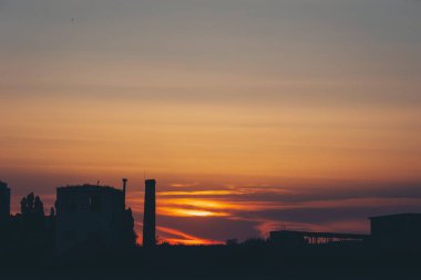 Renkli bulutlarla kaplı şehir manzarası, günbatımı arka planı. Akşamları gökyüzü turuncu. 