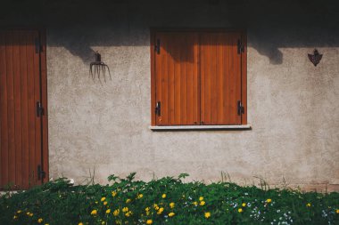 Geleneksel gri kapılı ahşap pencere ve kapı. Geleneksel Alp evinde ışık ve gölgeyle yıkanan duvar. Ön cephe ayrıntısı.