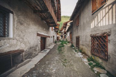 Chianale 'de kaldırımlı bir cadde, tipik ahşap evler. Chianale İtalya 'nın güzel bir dağlık köyüdür. İtalya, Pontechianale, 2023 'te kaldırımlı cadde boyunca uzanan büyüleyici evler ve binalar.