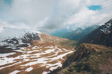 Alplerin manzarası çok güzel. Karla kaplı dağlar ve tepelerden oluşan kış manzarası. Uzakta kayalık bir zirve ve önünde karla kaplı tepeler. Mavi gökyüzü ile aydınlık bir günde çekildi..