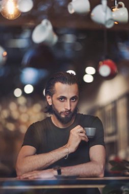 Erkek mağazası, kahve içilen bir yer. Pencereden dışarı bakıyor. Pencereden, sıcak kahvenin keyfini çıkarırken rahat bir kafede dinlenen genç ve düşünceli bir erkeğin...