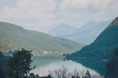 Suların, çevreleyen tepelerin ve ormanların klasik manzarası. İtalyan Alplerinde Lago di Pontechianale