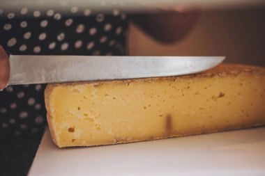 İşçi peyniri dilimliyor. Peynir doğrama yeri. Satıcı custers için peynir hazırlar. Organik ve tarım gıda konsepti. 