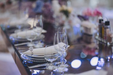 Çiçekler ve mumlar masada. Masayı mavi ve beyaz çiçekler süslüyor. Kutlama, parti ya da düğün resepsiyonu için bardaklar, tabaklar, mumlar ve çiçeklerle dolu güzel bir masa..