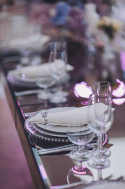 Çiçekler ve mumlar masada. Masayı mavi ve beyaz çiçekler süslüyor. Kutlama, parti ya da düğün resepsiyonu için bardaklar, tabaklar, mumlar ve çiçeklerle dolu güzel bir masa..