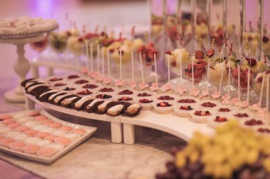 Çikolata. Çiçeklerle süslenmiş beyaz düğün pastası. Çilekli turta ve çöreklerle süslenmiş. Düğün için. Doğum günü partisinde renkli bir çikolata. Yiyecek ve tatlılar. yemek servisi.