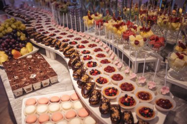 Çikolata. Çiçeklerle süslenmiş beyaz düğün pastası. Çilekli turta ve çöreklerle süslenmiş. Düğün için. Doğum günü partisinde renkli bir çikolata. Yiyecek ve tatlılar. yemek servisi.