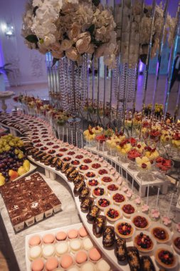 Altın nikahta lüks çikolata. Çiçeklerle süslenmiş şekerlemeler. Çöllerle, pastalarla, çilekli tartlarla, keklerle ve kurabiyelerle süslenmiş. Düğün için. Resepsiyon çörekleri. Yemek servisi.