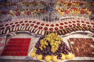 Altın nikahta lüks çikolata. Çiçeklerle süslenmiş şekerlemeler. Çöllerle, pastalarla, çilekli tartlarla, keklerle ve kurabiyelerle süslenmiş. Düğün için. Resepsiyon çörekleri. Yemek servisi.