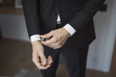 İş adamı ceket giyer, erkek eli yakın çekim yapar, damat düğün töreninden önce hazırlanır. düğün detayları