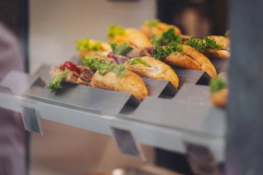 Pastanenin vitrininde yeşil marullu lezzetli sandviçler. Pastanede perakende satış yapan lezzetli taze kruvasanları kapatın.. 