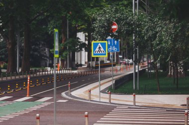 Bir sürü ağacı olan şehir caddesi. Asfalt yolda bisiklet yolu ile yaya geçidi üzerinde yeni bir trafik güvenliği tümseği. yol işaretleri. 