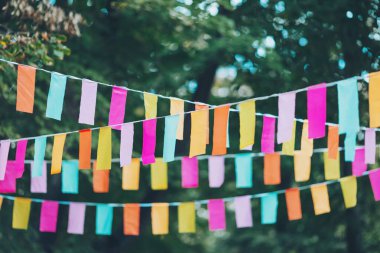 Parti bayrakları bir partide süslenmişti. Bir şehir tatili geçmişi. Yaz parkında renkli mini bayraklar. Doğum günü partisi için dekorasyon. Popüler festivallerin geleneksel dekorasyonu, etkinlikler