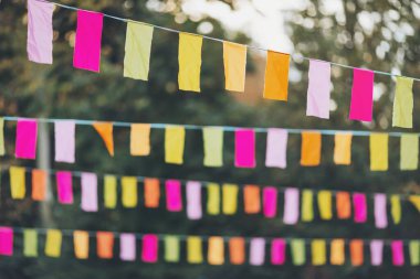 Parti bayrakları bir partide süslenmişti. Bir şehir tatili geçmişi. Yaz parkında renkli mini bayraklar. Doğum günü partisi için dekorasyon. Popüler festivallerin geleneksel dekorasyonu, etkinlikler