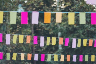 Parti bayrakları bir partide süslenmişti. Bir şehir tatili geçmişi. Yaz parkında renkli mini bayraklar. Doğum günü partisi için dekorasyon. Popüler festivallerin geleneksel dekorasyonu, etkinlikler