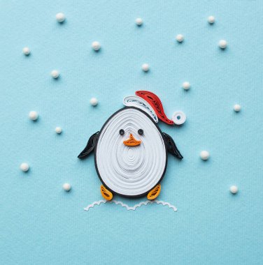Noel Baba 'daki komik ve komik bir penguen. Kürkü ve ponponu olan kırmızı bir Noel şapkası. Quilling tekniğinde Noel tebrik kartı. El yapımı. Evde el işi. Hobi, ev ofisi..