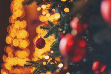 Kırmızı ağaç süslemesi ve altın çelengi olan bir arka plan. Noel ağacında kırmızı Noel balosu