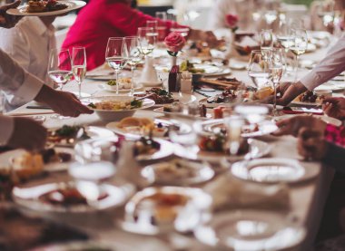 İnsanlar bir restoranda öğle veya akşam yemeği yiyorlar. Tabaklar masaya. Garson, şenlikli bir etkinlikte et tabağı taşıyor..